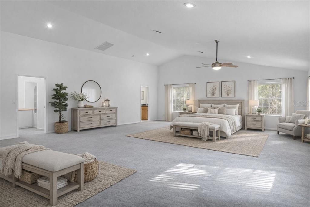 A spacious bedroom features a vaulted ceiling, neutral decor, a large bed, and gray carpeting — 5248 NEFF LAKE ROAD, BROOKSVILLE, FL