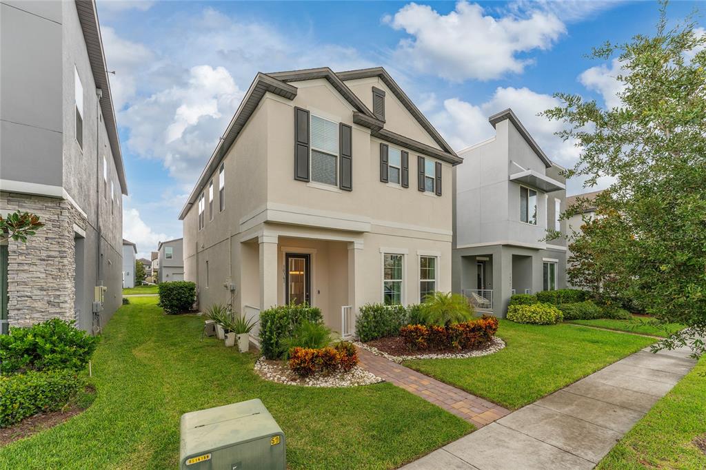 A two-story suburban house with a beige exterior, a front porch, and a landscaped yard — 10361 AUSTRINA OAK LOOP, WINTER GARDEN, FL
