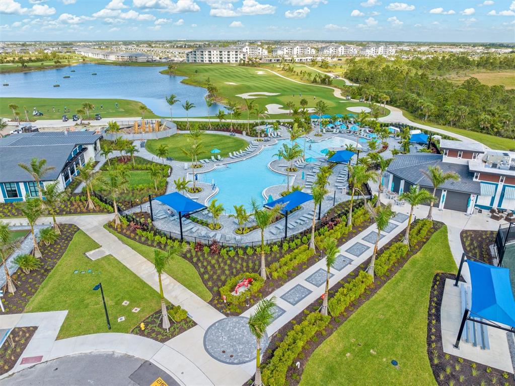 An aerial view shows a resort-style swimming pool with lounge chairs and blue shade structures — 12550 GALAPAGOS COURT UNIT 208, VENICE, FL