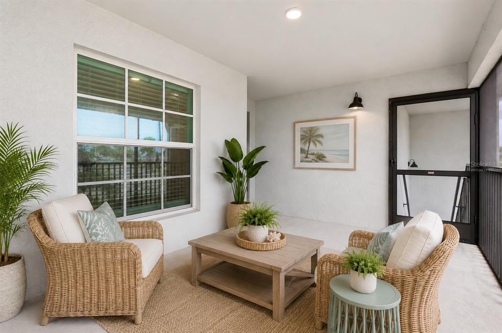 A covered patio features two wicker chairs, a wooden coffee table, and a large window — 12550 GALAPAGOS COURT UNIT 208, VENICE, FL