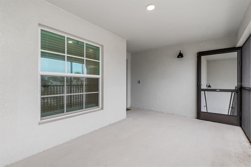 A covered balcony with a window, a screen door, and a light fixture — 12550 GALAPAGOS COURT UNIT 208, VENICE, FL