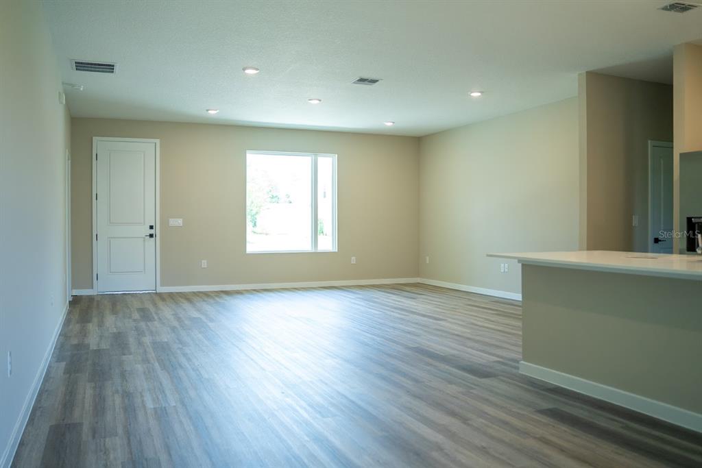 An empty room features light-colored walls, recessed lighting, and wood-look vinyl plank flooring — 117 BAYSIDE DRIVE, PALM COAST, FL