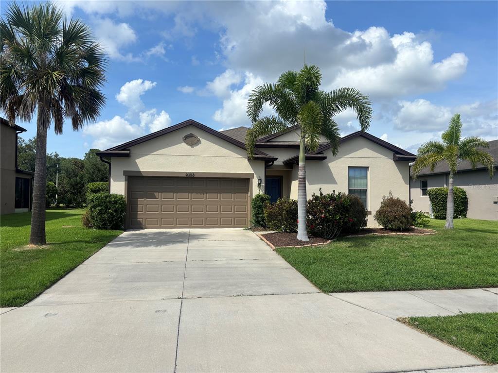 A beige, single-story house with a two-car garage and palm trees in the front yard — 6122 100TH AVENUE E, PARRISH, FL