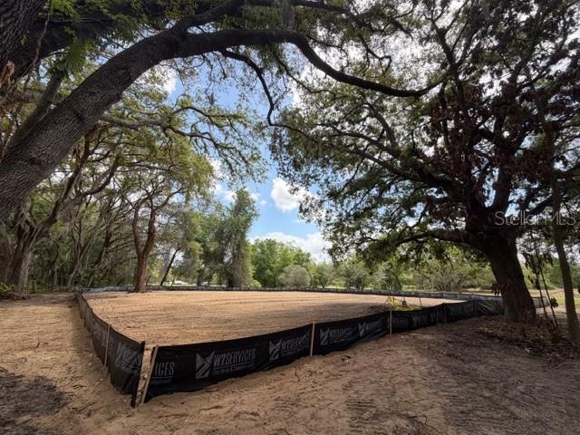 A cleared, sandy residential lot is enclosed by black silt fencing beneath large oak trees — 17144 PHIL C PETERS ROAD, WINTER GARDEN, FL