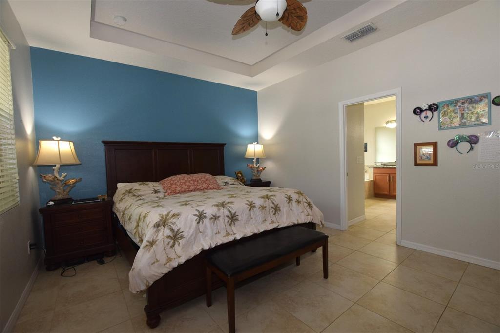 A bedroom features a dark wood bed, a blue accent wall, and tiled flooring — 573 KISTLER CIRCLE, CLERMONT, FL