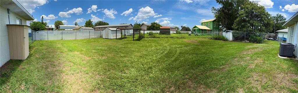 A wide-angle view of a large, grassy backyard with a chain-link fence and storage sheds — 8 N HENDRY AVENUE, FORT MEADE, FL