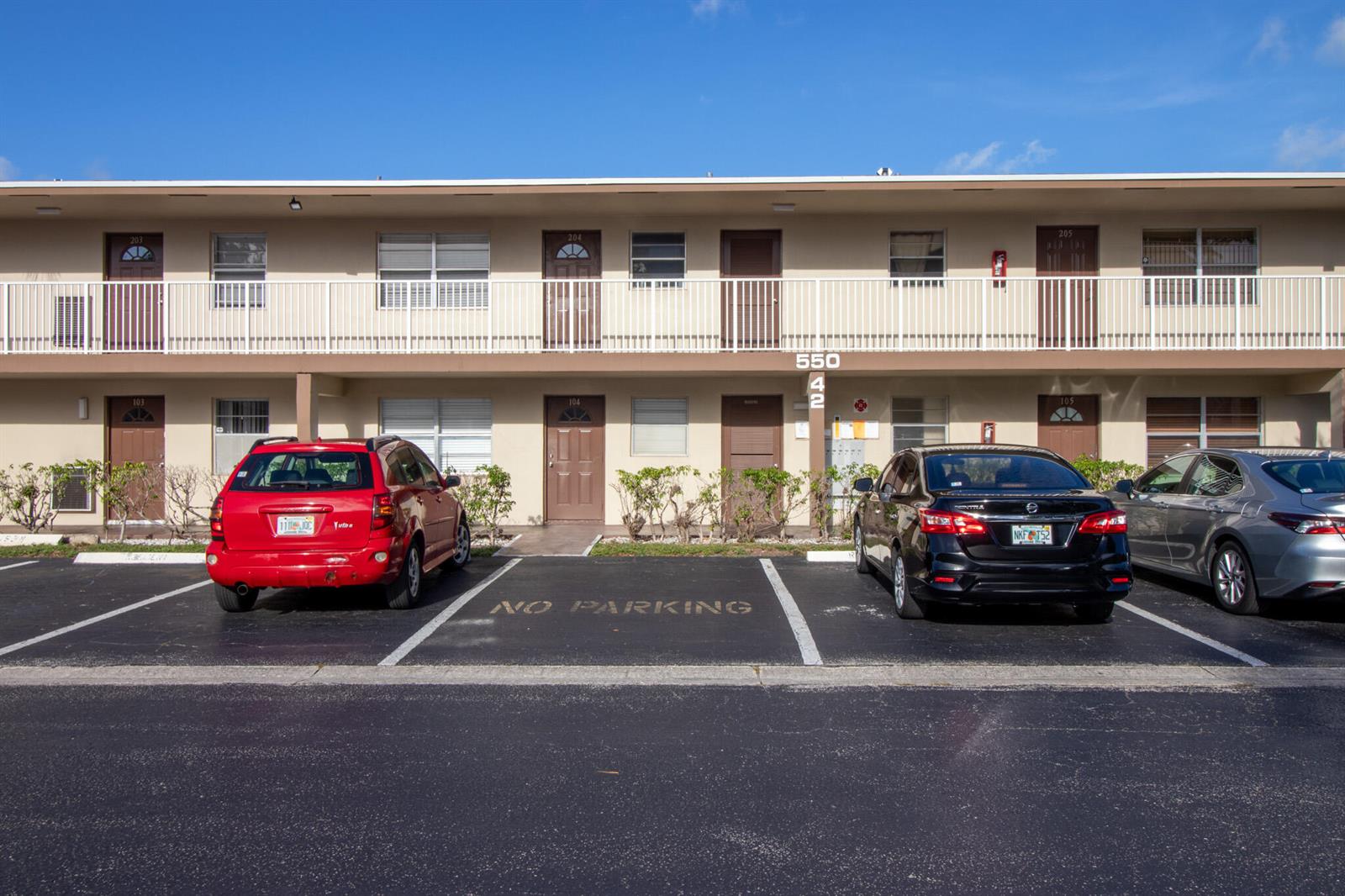 A two-story apartment building exterior features a parking lot with three cars parked in front — 550 NW 77th Avenue # 204, Margate FL 33063, MARGATE, FL
