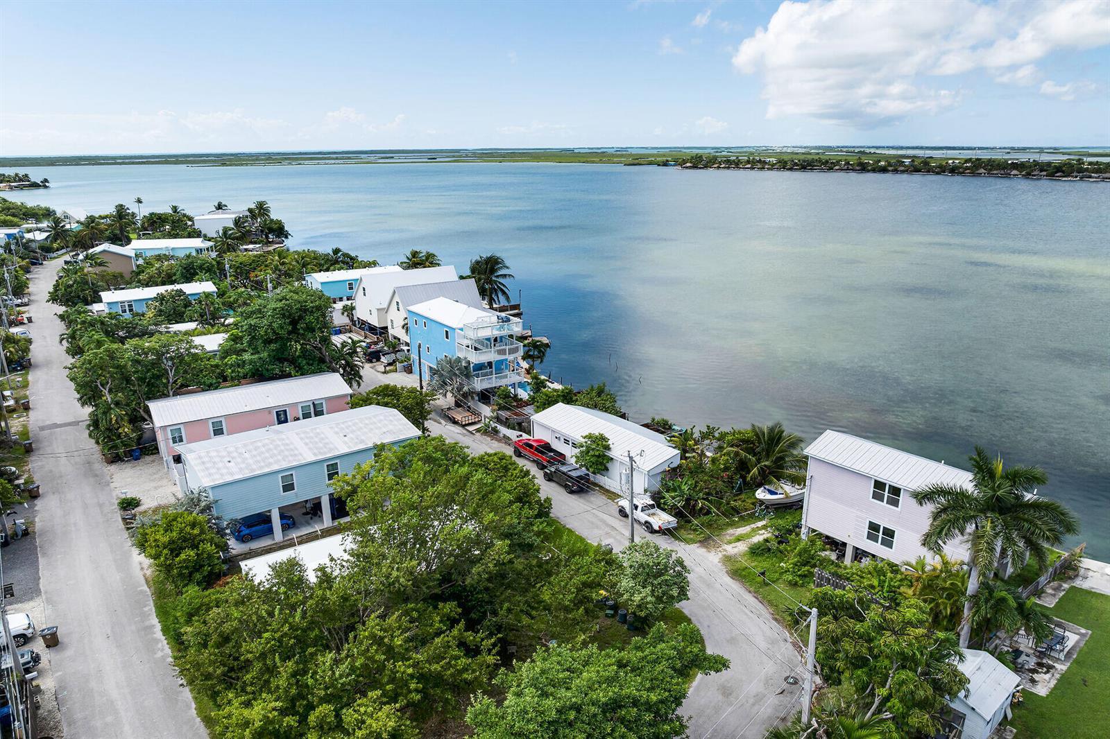 An aerial view shows waterfront houses along a road with palm trees and vegetation — 4 Shore Drive, Key West FL 33040, KEY WEST, FL