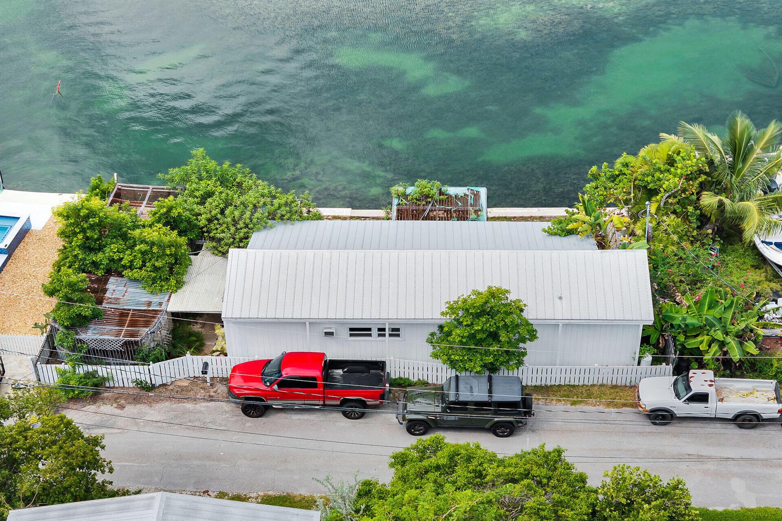 An aerial view shows a white house with a metal roof parked with three vehicles — 4 Shore Drive, Key West FL 33040, KEY WEST, FL