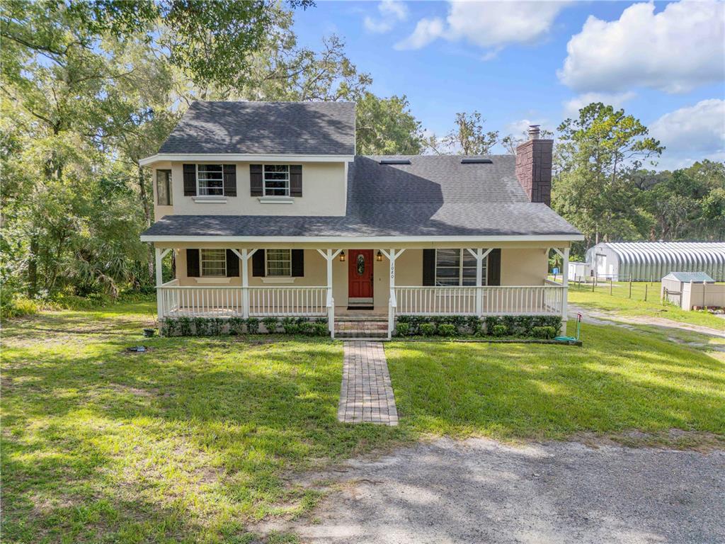 A two-story house with a front porch, brick walkway, and a dark shingled roof — 1080 E FRENCH AVENUE, ORANGE CITY, FL