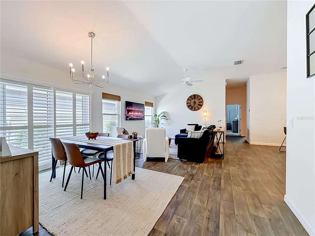 A dining area with a chandelier and a living room with a fireplace and sofa — 6231 ATKINSON LANE, THE VILLAGES, FL