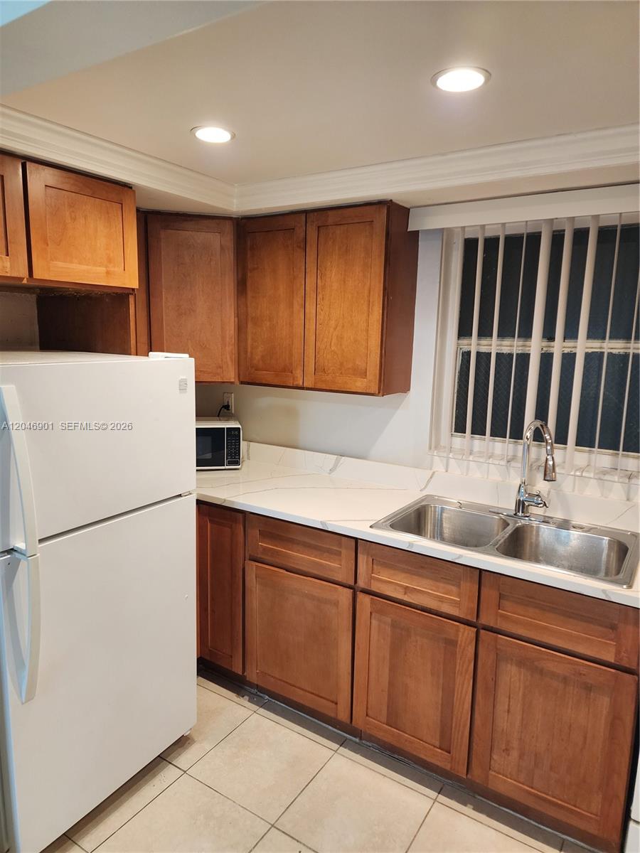 A kitchen features wood cabinets, white countertops, a double-basin sink, and a white refrigerator — MIAMI, FL
