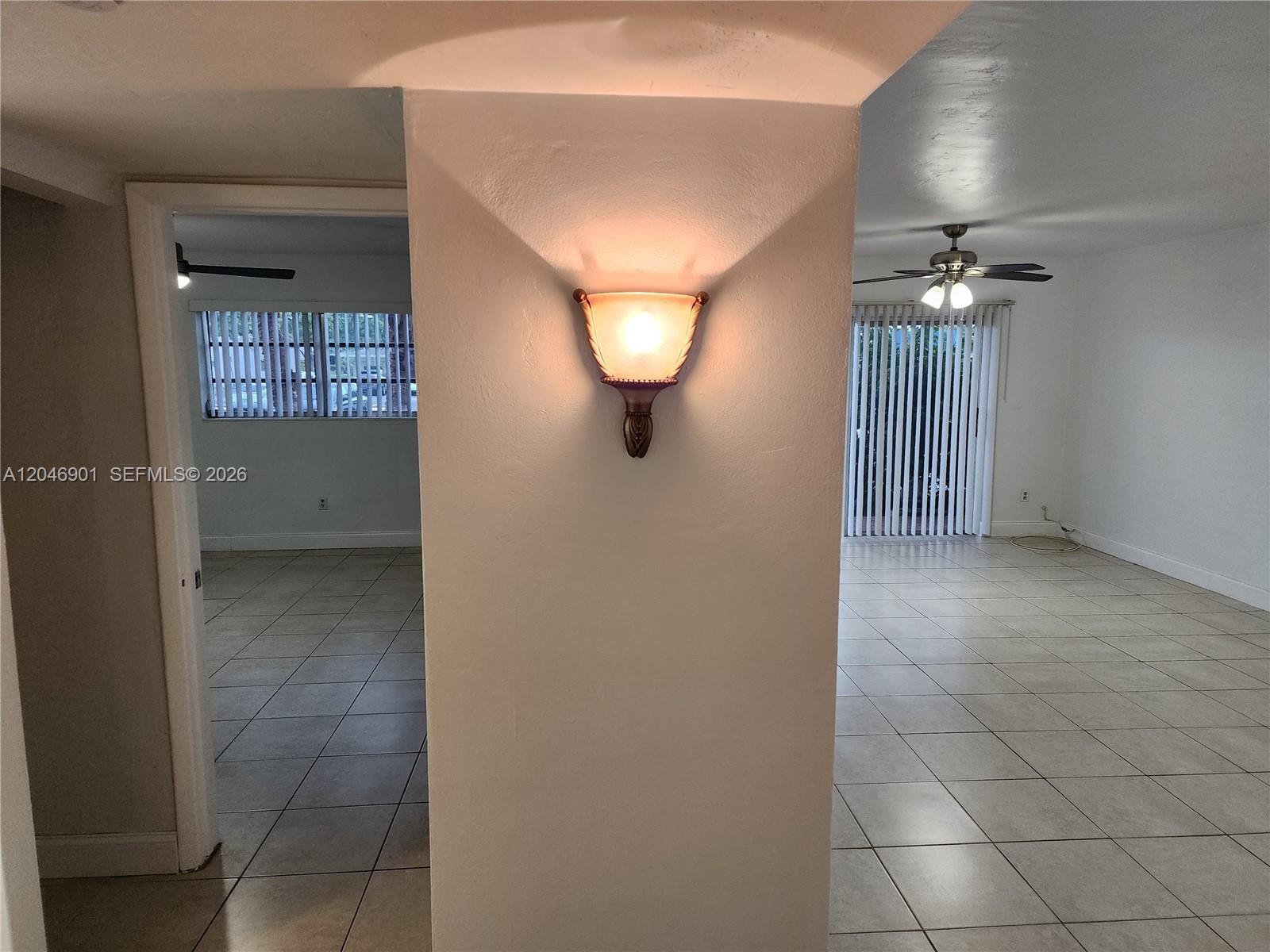 A wall-mounted light fixture sits on a pillar between two tiled living areas — MIAMI, FL