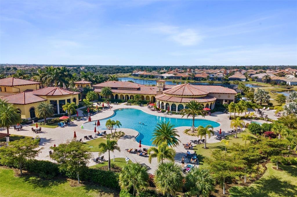 An aerial view shows a large resort-style swimming pool surrounded by palm trees and buildings — 20120 RAGAZZA CIRCLE UNIT 202, VENICE, FL