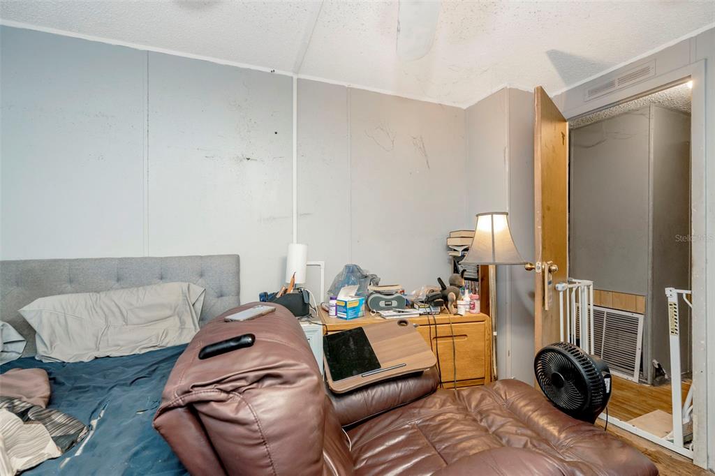 A bedroom features a bed, a brown recliner, a wooden dresser, and an open doorway — 35913 VALLEYBROOK AVENUE, ZEPHYRHILLS, FL