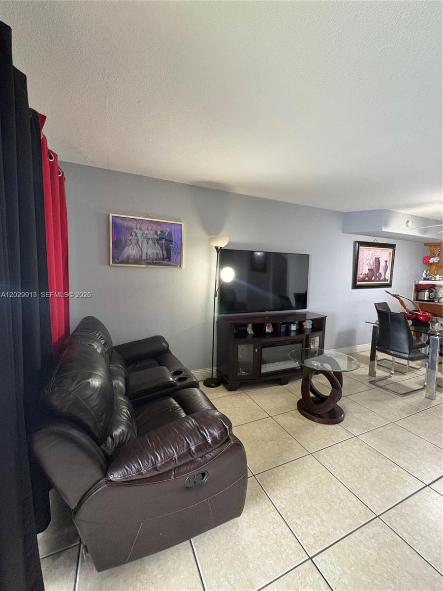 A living room features a dark leather sofa, a television on a stand, and tile flooring — 2778 W 60th St # 45, Hialeah FL 33016, HIALEAH, FL