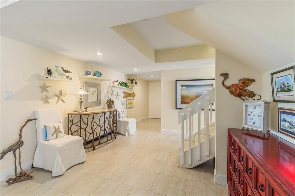 A bright entryway features light tile floors, a staircase, and coastal-themed decor on the walls — 440 S GULFVIEW BOULEVARD UNIT 1705, CLEARWATER BEACH, FL