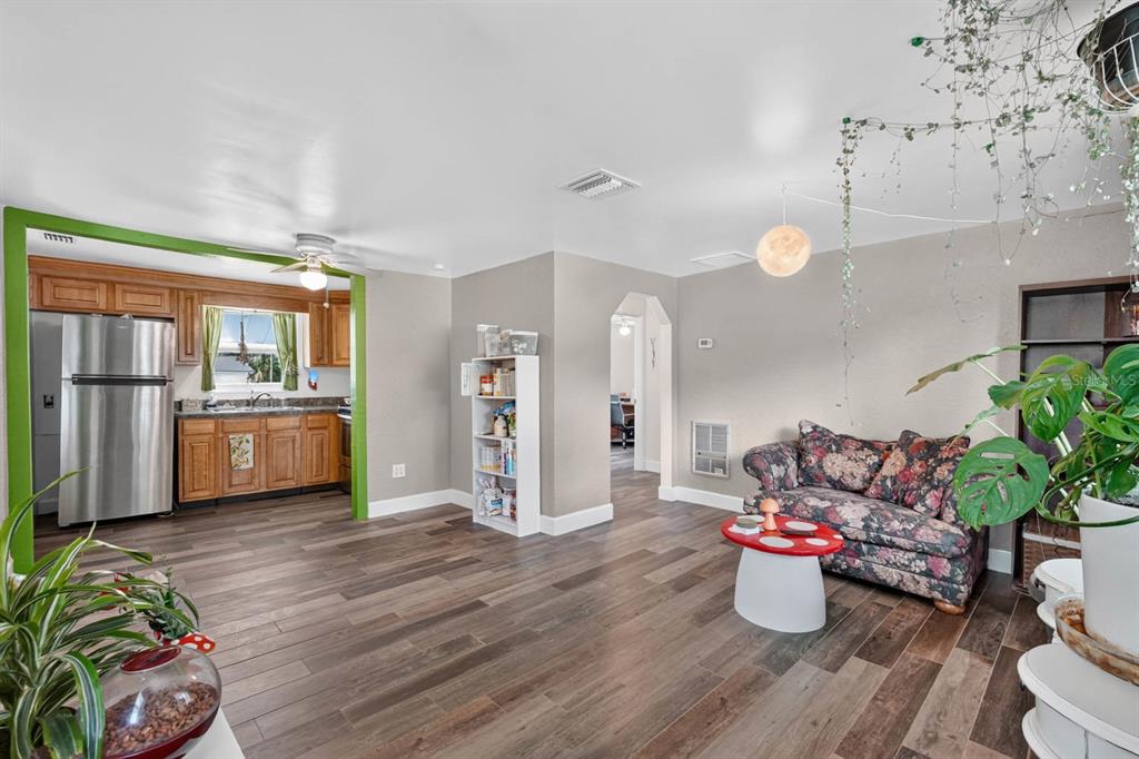 A living room with wood-look flooring, a floral sofa, and an open kitchen with cabinets — 277 DEBARY DRIVE, DEBARY, FL