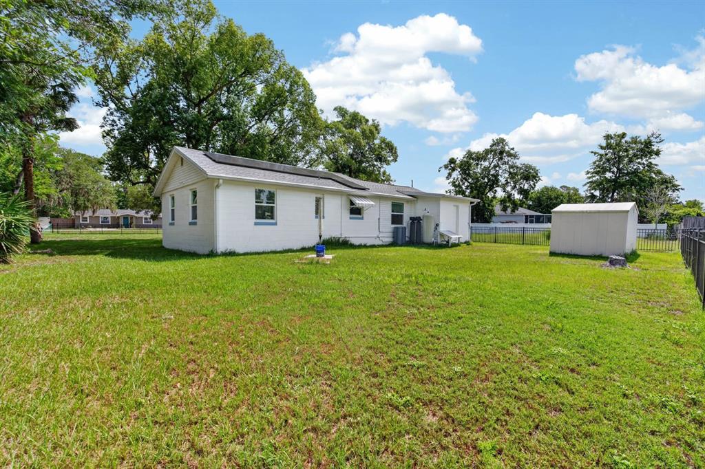 The exterior of a white single-story house features a large grassy backyard and a shed — 277 DEBARY DRIVE, DEBARY, FL