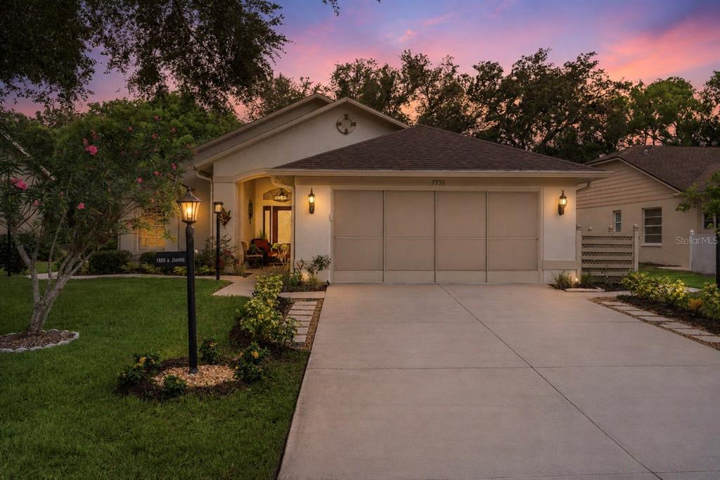 A single-story house with a beige stucco exterior, a two-car garage, and a concrete driveway — 7350 ROSEMONT LANE, SPRING HILL, FL