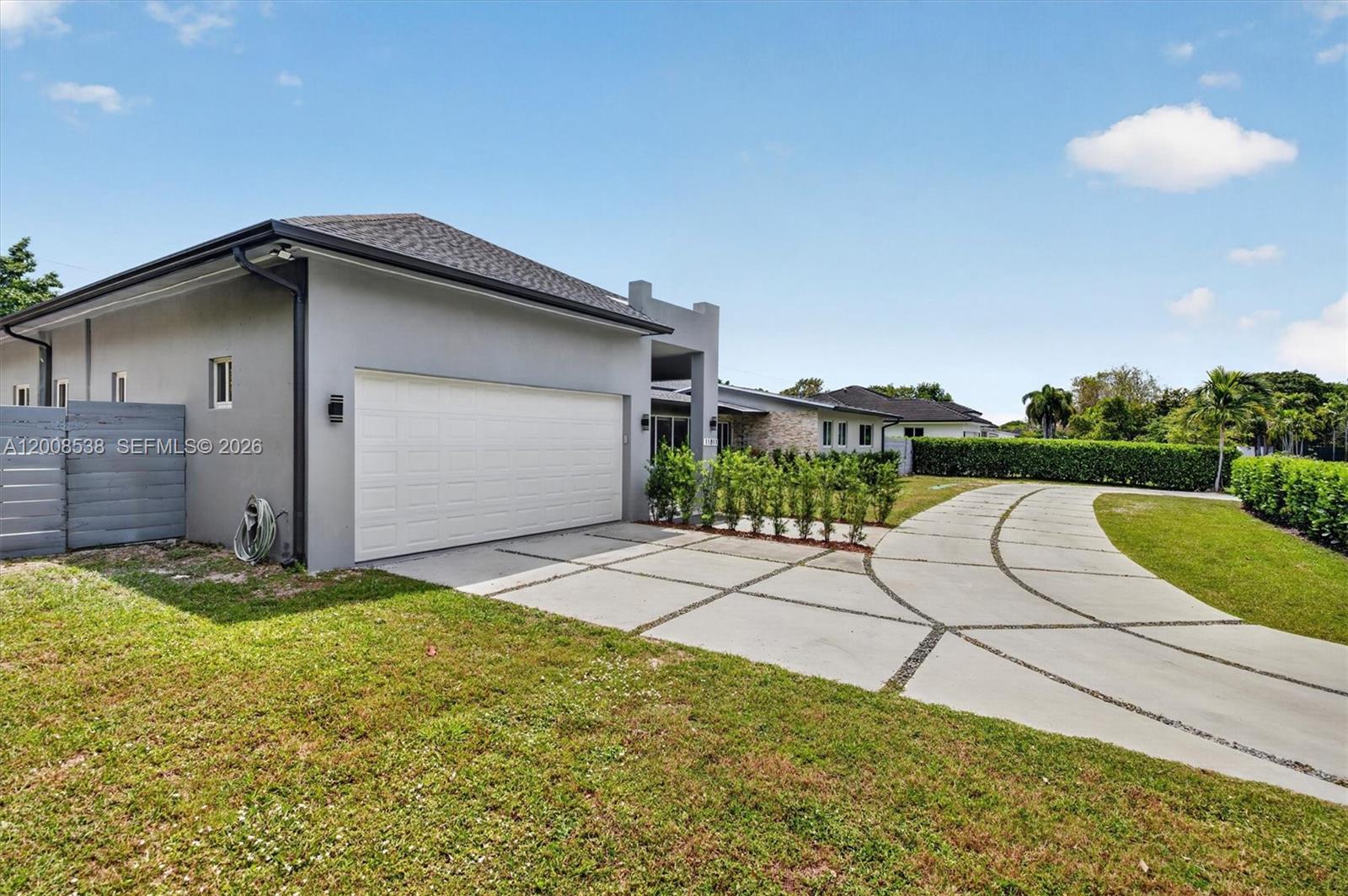 A gray house with a white garage door and a curved concrete driveway — 11811 SW 82nd Rd, Miami FL 33156, MIAMI, FL