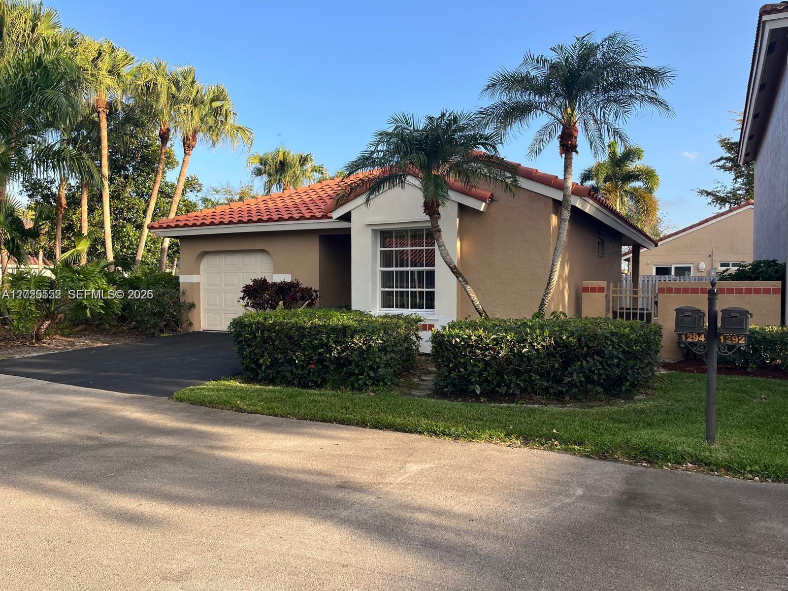 A single-story house with a red tile roof, tan stucco walls, and two palm trees — 1294 Seagrape Cir, Weston FL 33326, WESTON, FL