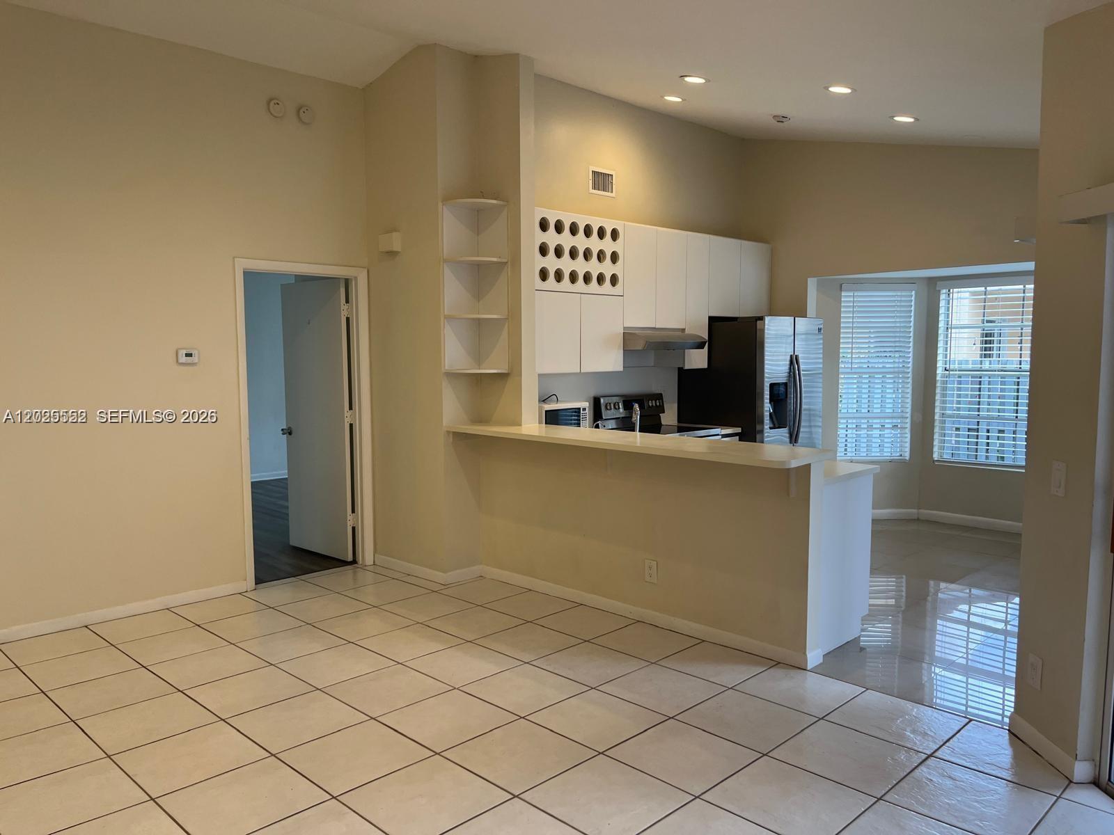 An open-concept kitchen features white cabinets, a breakfast bar, and tiled flooring — 1294 Seagrape Cir, Weston FL 33326, WESTON, FL