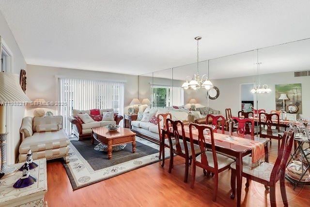 A living and dining room featuring wood floors, mirrored walls, and traditional furniture — 7703 Camino Real # A105, Miami FL 33143, MIAMI, FL