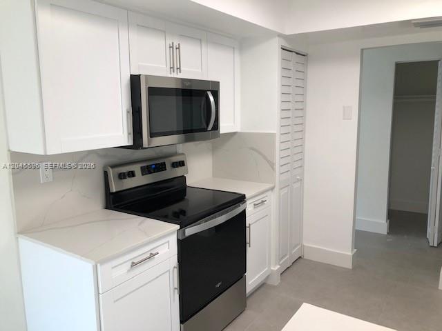 A modern kitchen features white cabinets, stainless steel appliances, and light-colored stone countertops — 9124 SW 112 CT, Miami FL 33176, MIAMI, FL
