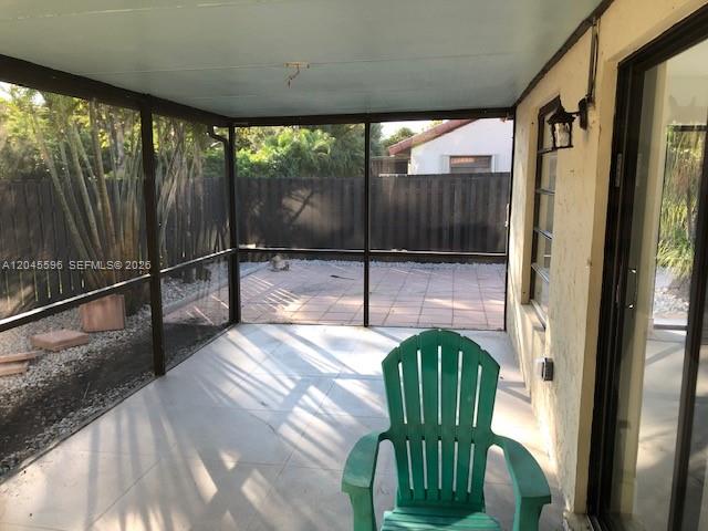 A screened-in patio features a green chair, tiled flooring, and a view of a backyard — 9124 SW 112 CT, Miami FL 33176, MIAMI, FL