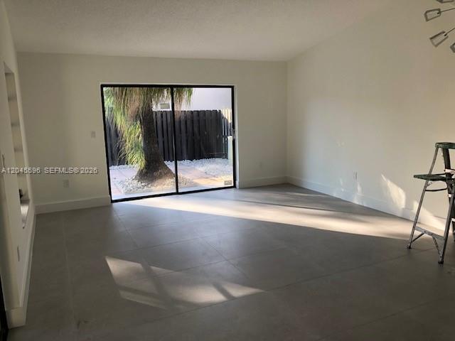 An empty room features light-colored tile flooring, white walls, and a sliding glass door — 9124 SW 112 CT, Miami FL 33176, MIAMI, FL