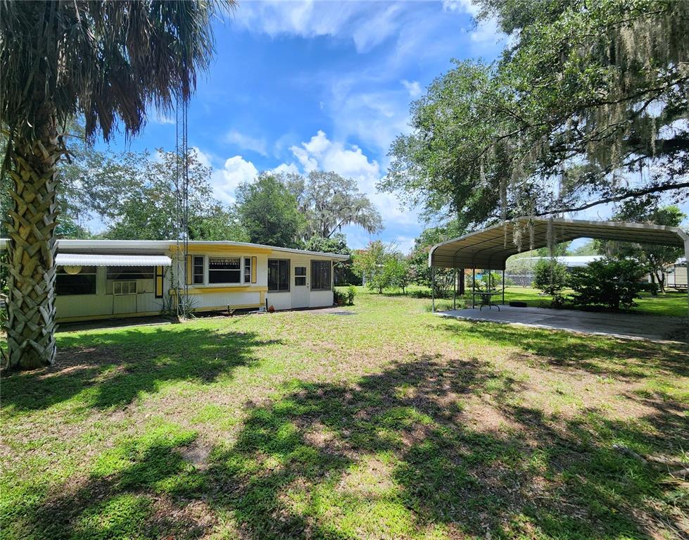A single-story house with a yellow trim exterior and a detached metal carport — 9997 SE 167TH LANE, SUMMERFIELD, FL