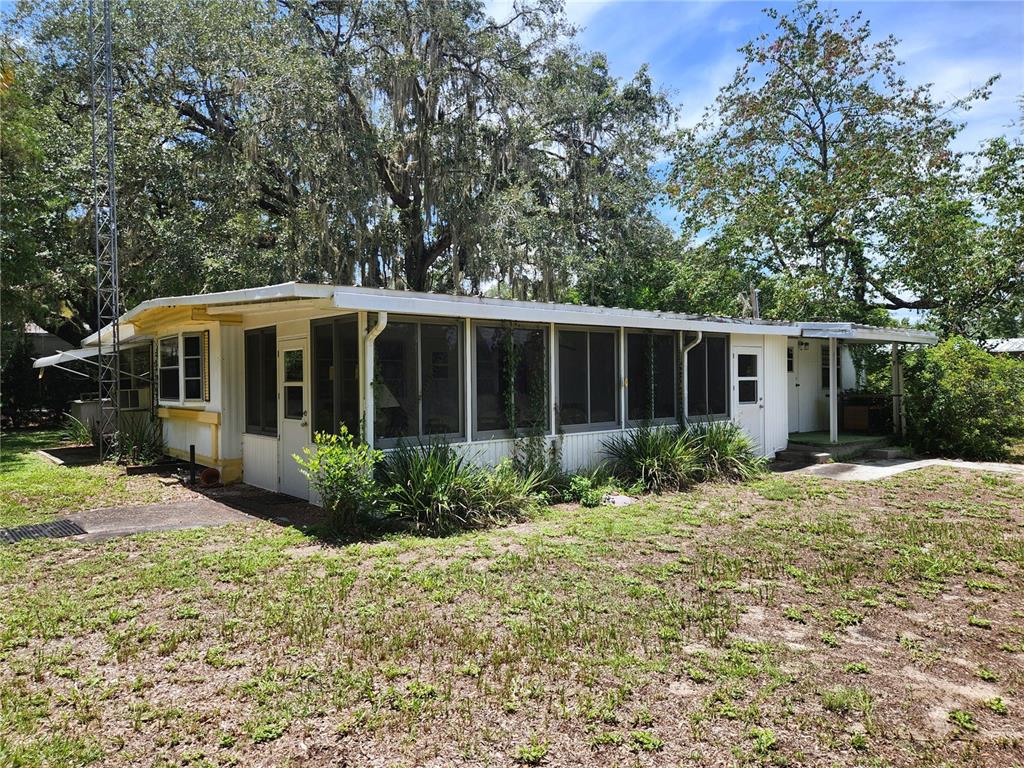 A single-story mobile home with a screened-in porch sits on a grassy lot with trees — 9997 SE 167TH LANE, SUMMERFIELD, FL