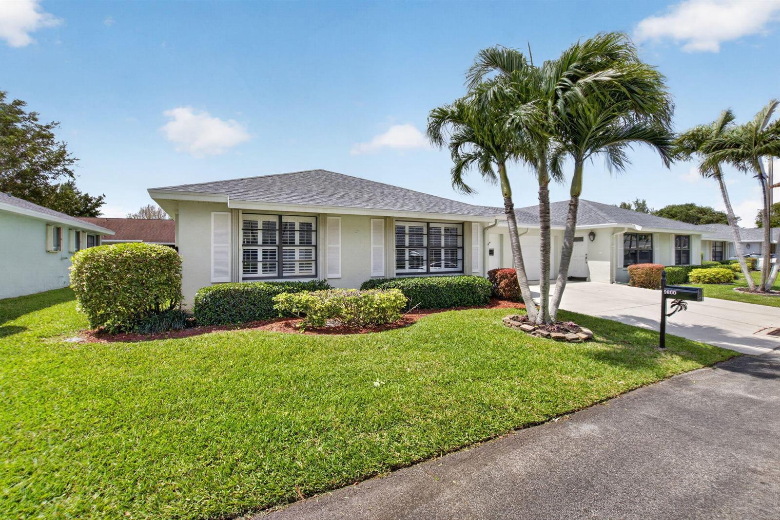 A single-story house with a green lawn, palm trees, and a concrete driveway — 9800 Tabebuia Tree Drive # A, Boynton Beach FL 33436, BOYNTON BEACH, FL