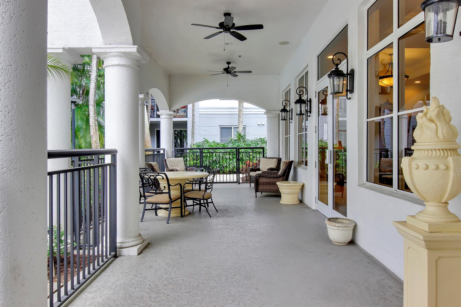 A covered outdoor patio features white columns, ceiling fans, and patio furniture — 1660 Renaissance Commons Boulevard # 2118, Boynton Beach FL 33426, BOYNTON BEACH, FL