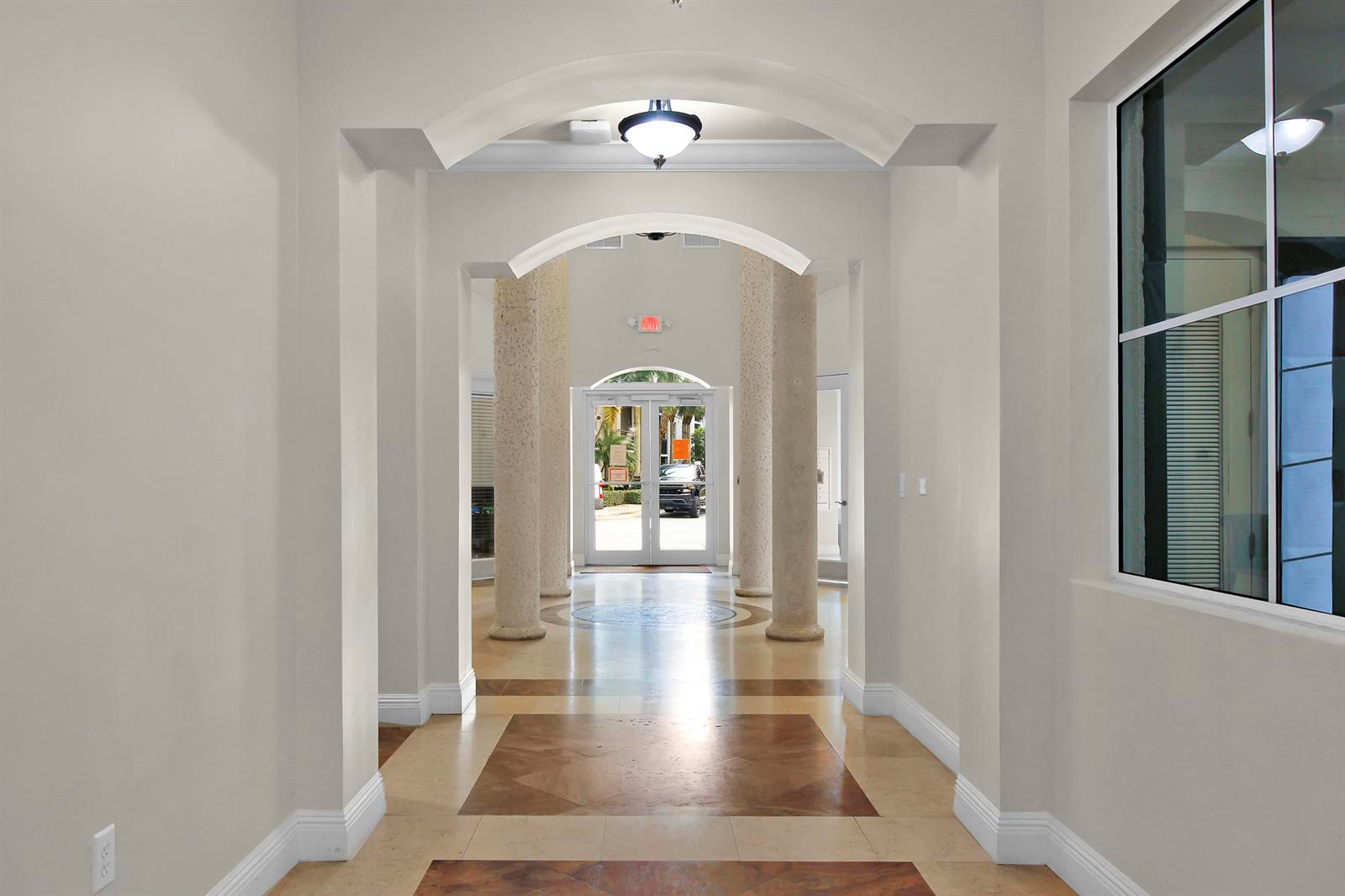 A hallway with arched ceilings, stone columns, and tile flooring leads to a glass entrance door — 1660 Renaissance Commons Boulevard # 2118, Boynton Beach FL 33426, BOYNTON BEACH, FL