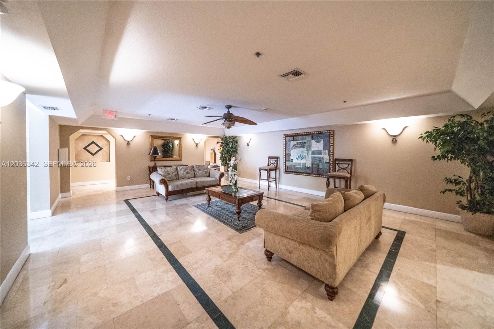 A spacious living area features beige tile floors, two sofas, a coffee table, and wall sconces — 1650 Coral Way # 507, Miami FL 33145, MIAMI, FL