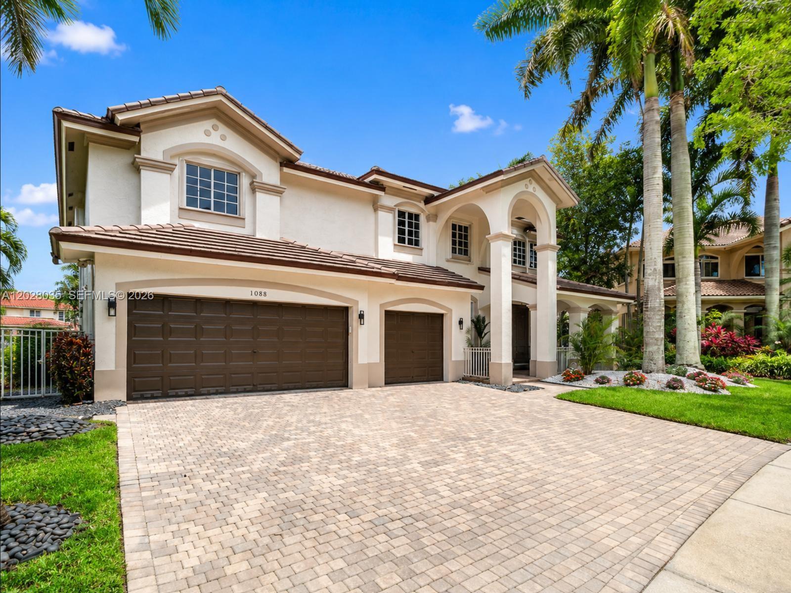 A two-story house with a three-car garage and a paved driveway under a blue sky — 1088 Skylark Dr, Weston FL 33327, WESTON, FL