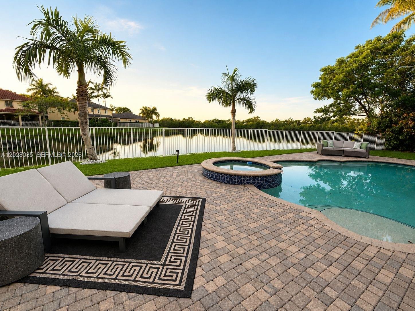 A patio features a swimming pool, a hot tub, lounge chairs, and a lake view — 1088 Skylark Dr, Weston FL 33327, WESTON, FL