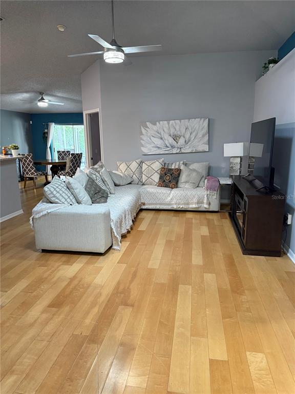 A living room features light hardwood floors, a sectional sofa, and a television console — 10707 PALAISEAU COURT, ORLANDO, FL