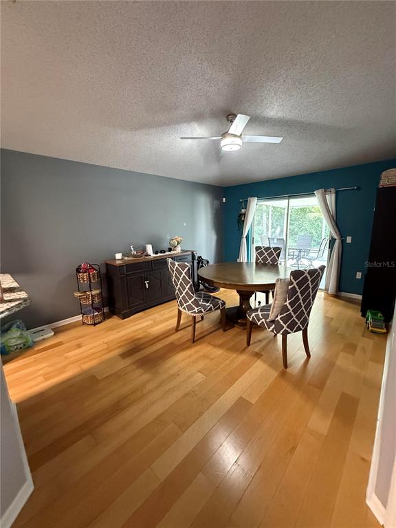 A dining room features a wooden table, patterned chairs, a dark sideboard, and hardwood floors — 10707 PALAISEAU COURT, ORLANDO, FL