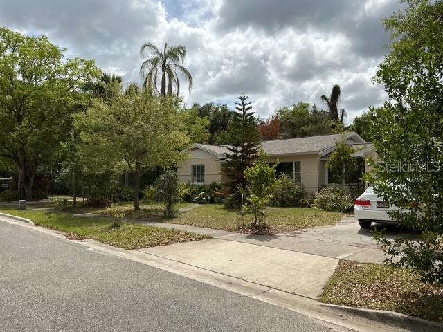 A single-story house with a light-colored exterior sits behind a lawn and a parked car — 210 ALPINE DRIVE, MAITLAND, FL