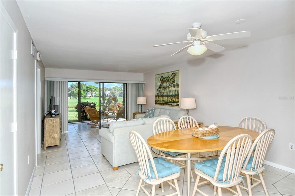 A dining area with a wooden table and chairs sits in front of a living room — 5133 WILLOW LINKS UNIT 11, SARASOTA, FL