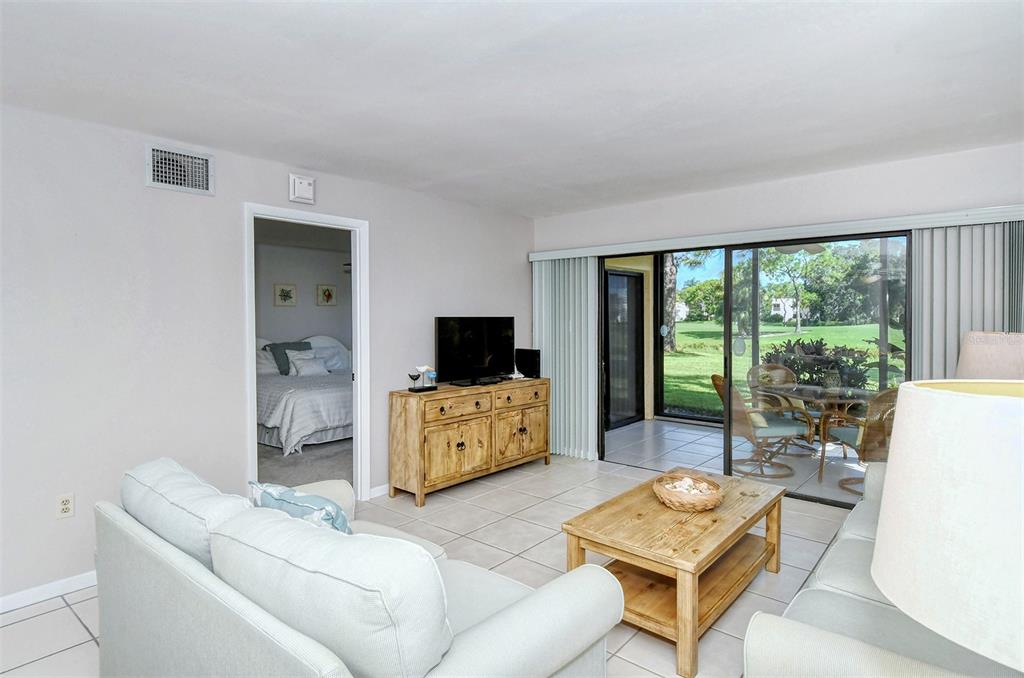 A living room with tile floors, a wooden media console, and a sliding glass door — 5133 WILLOW LINKS UNIT 11, SARASOTA, FL