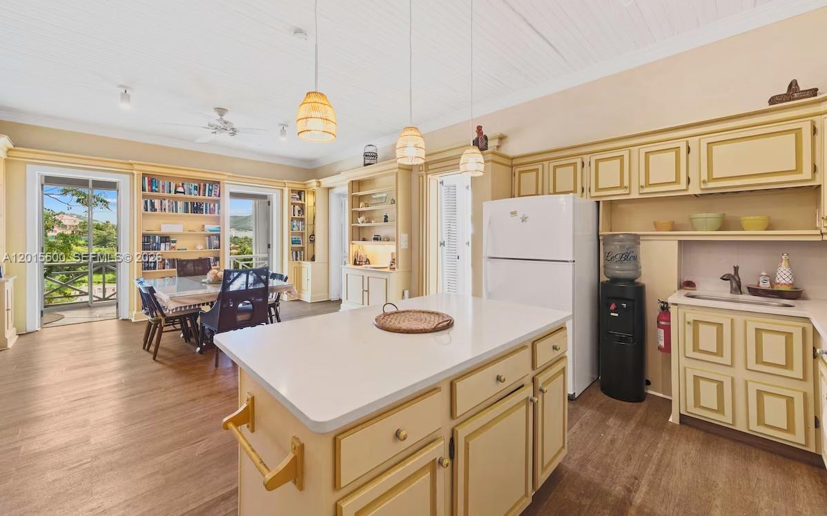 A kitchen with yellow cabinets, a white island, and an adjacent dining area with bookshelves — 12 Murphy Gade, VI 00802, VI