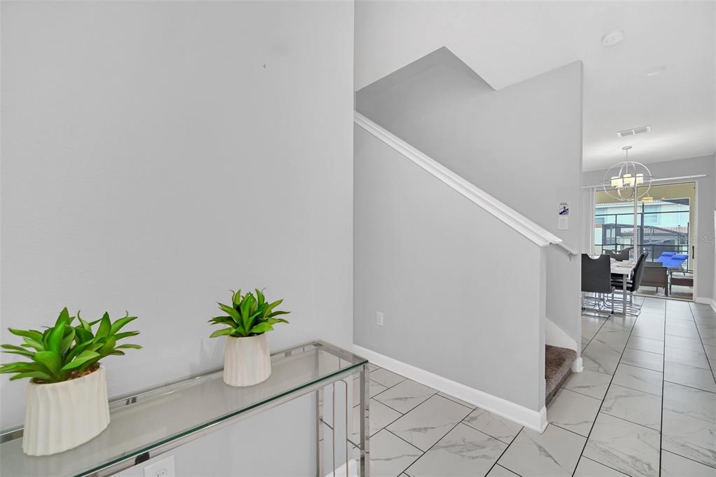 A foyer with a glass console table leads to a staircase and an open dining area — 1569 PLUNKER DRIVE, DAVENPORT, FL