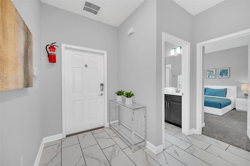 A tiled entryway features a white front door, a glass console table, and a fire extinguisher — 1569 PLUNKER DRIVE, DAVENPORT, FL