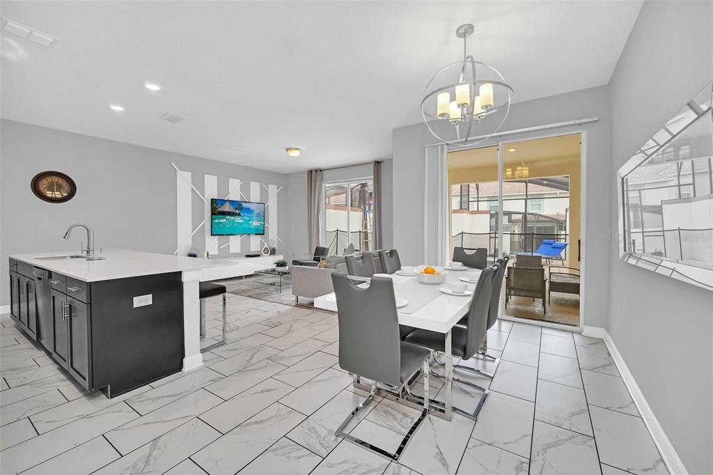 An open-concept kitchen, dining area, and living room featuring tile flooring and a sliding door — 1569 PLUNKER DRIVE, DAVENPORT, FL