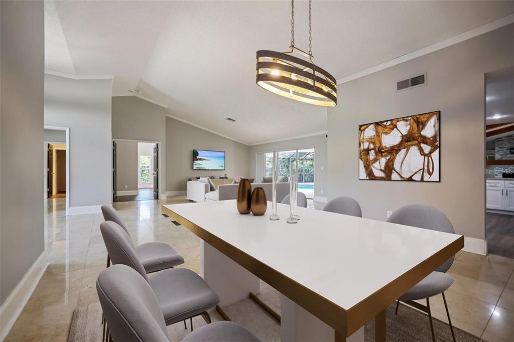 A dining room with a white table, grey chairs, and a modern oval light fixture — 3297 VALEMOOR DRIVE, PALM HARBOR, FL