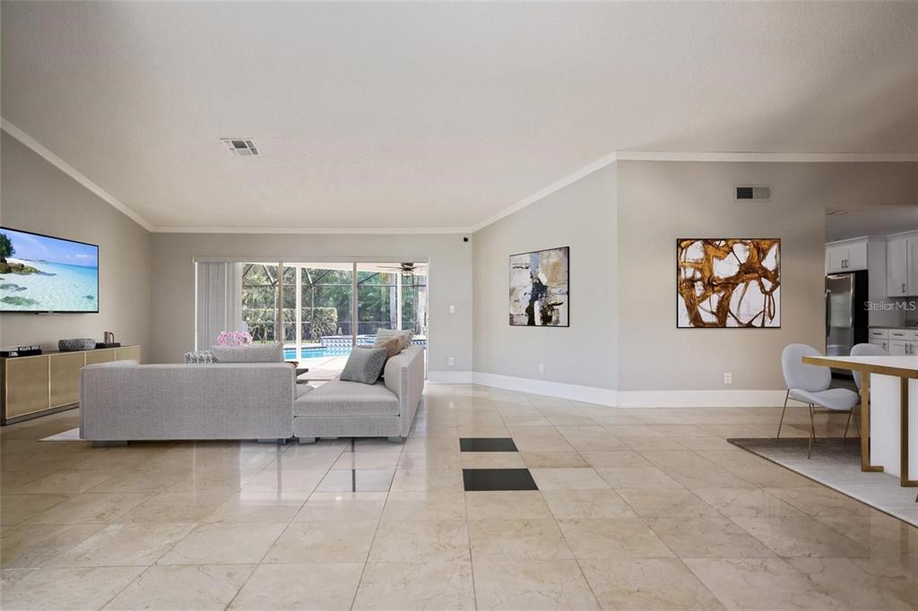 A spacious living room with light tile floors, a gray sectional sofa, and pool views — 3297 VALEMOOR DRIVE, PALM HARBOR, FL